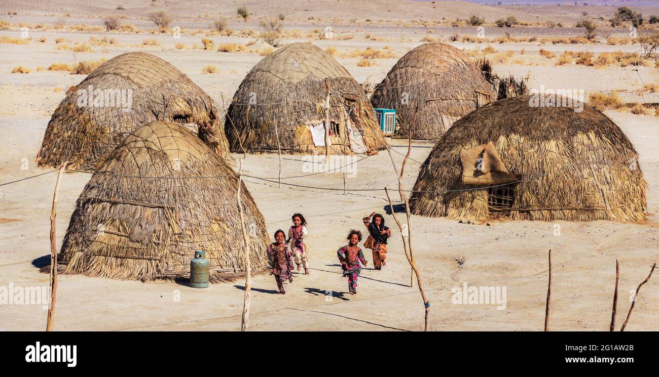 Baloch children playing next to their traditional houses in Nikshahr County, Sistan and Baluchestan Province, Iran. Stock Photo