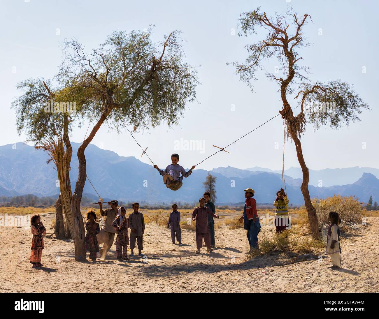 Baloch children (Baluch) playing next to their traditional houses in Nikshahr County, Sistan and Baluchestan Province, Iran. Stock Photo