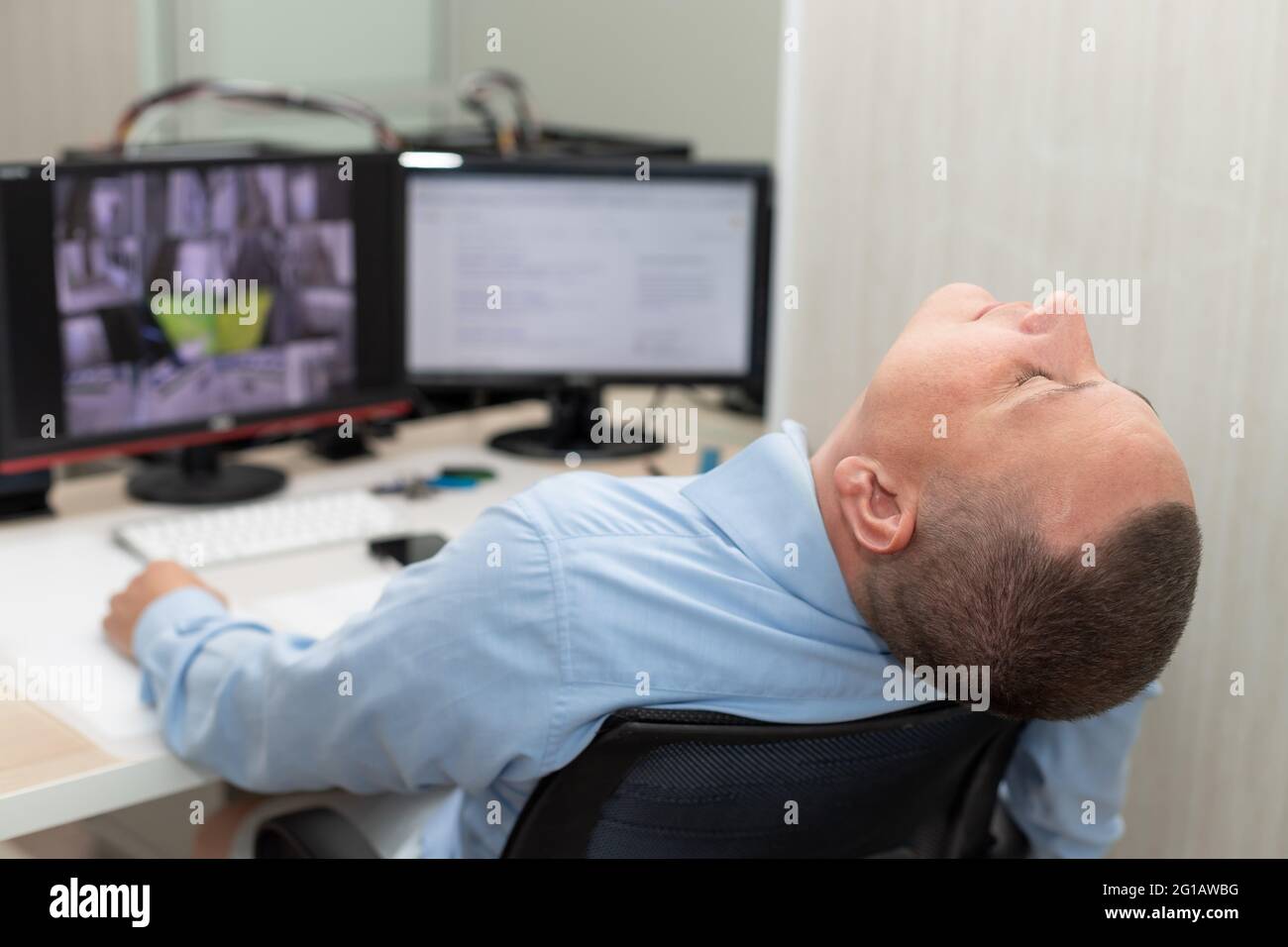 security guard sleeping at workplace in surveillance room Stock Photo