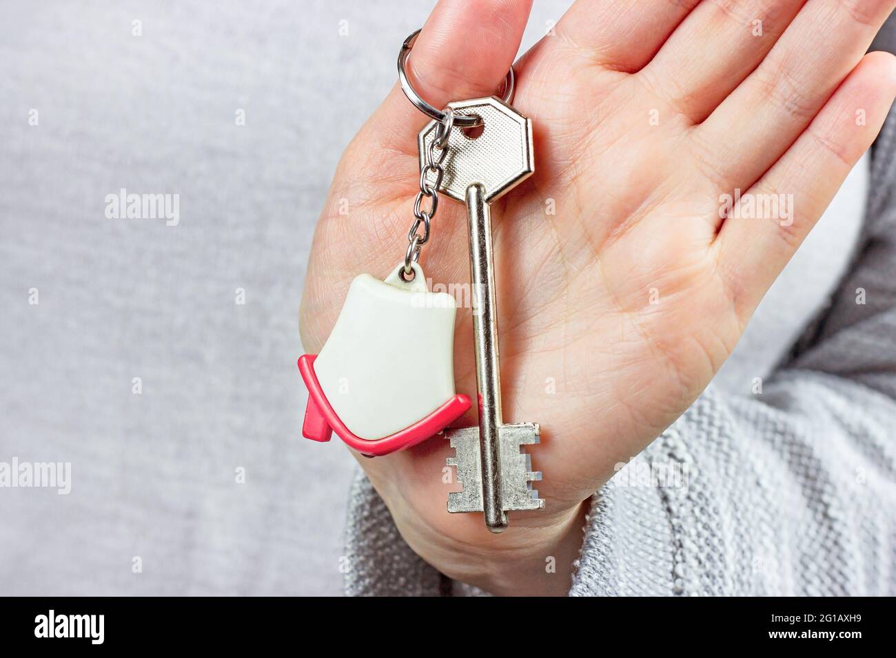 Caucasian woman hands holding the keychain with the keys and small house key ring close up. Apartment renter, real estate ownership, property purchase Stock Photo