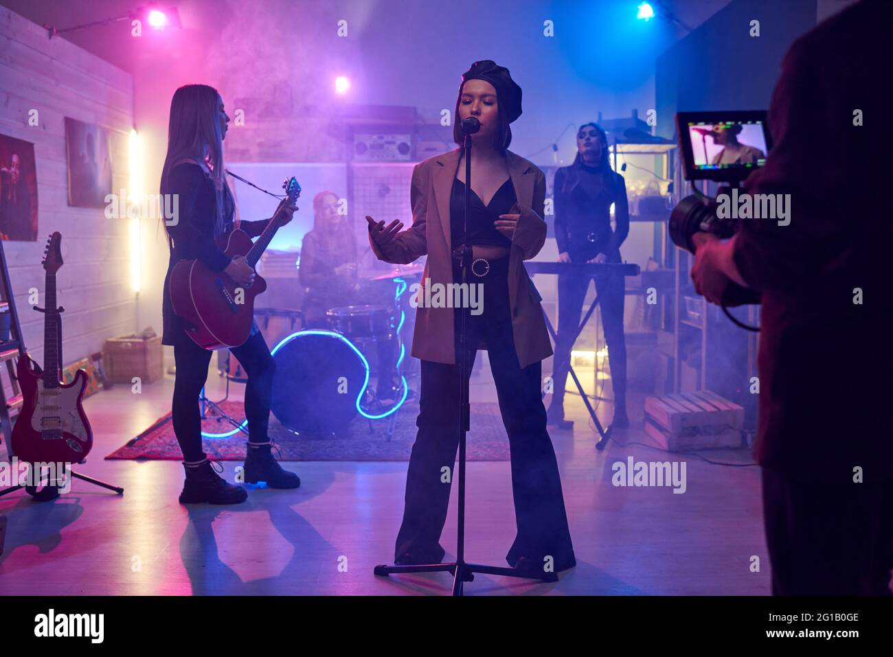Young female singing on stage in front of cameraman shooting music video Stock Photo