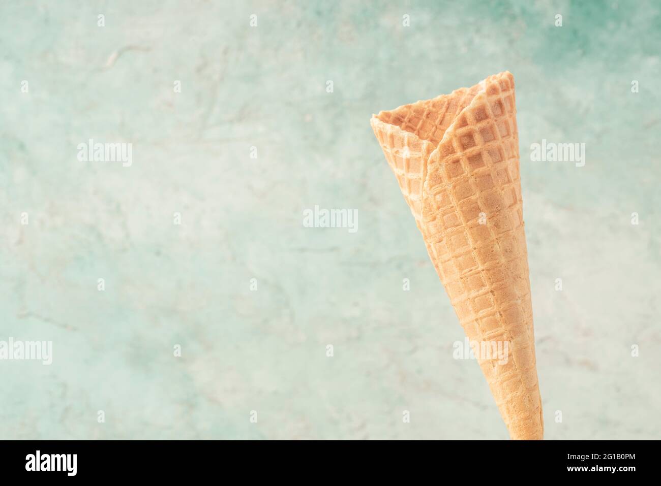 https://c8.alamy.com/comp/2G1B0PM/closeup-of-an-empty-ice-cream-cone-over-green-background-with-copy-space-2G1B0PM.jpg