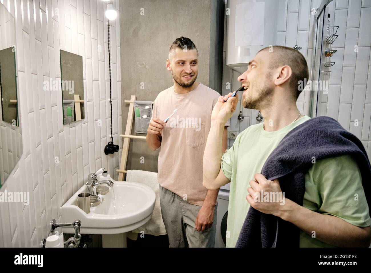 Two young gay men brushing teeth in bathroom in the morning Stock Photo