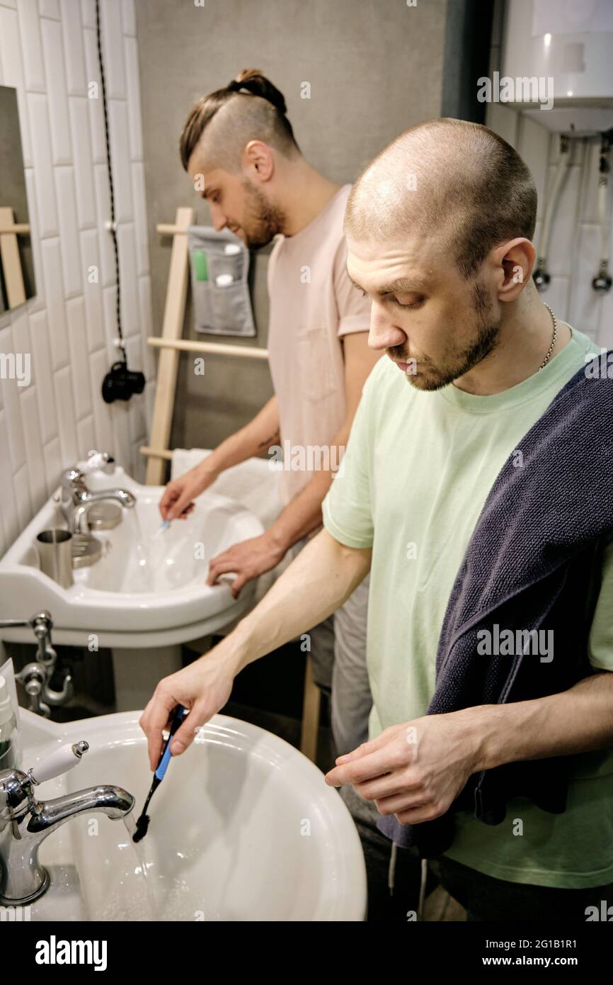 two young gay men washing toothbrushes after brushing teeth Stock Photo
