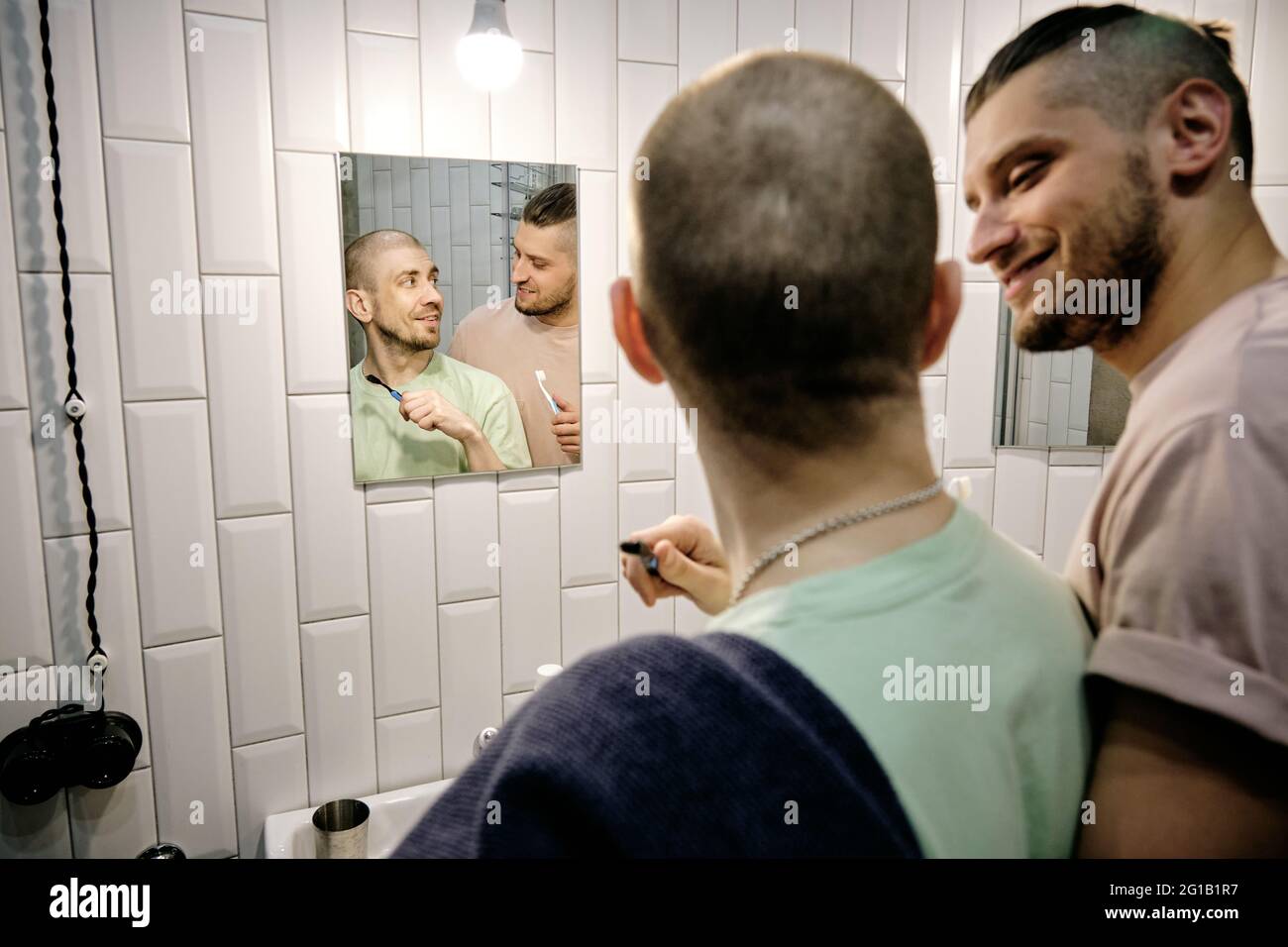 Happy young gay man looking at his boyfriend in bathroom Stock Photo