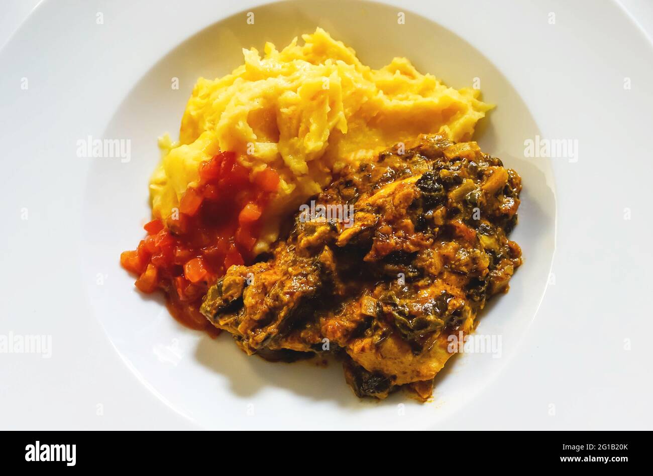 Chicken curry with spinach, diced tomato, sweet potato mash Stock Photo