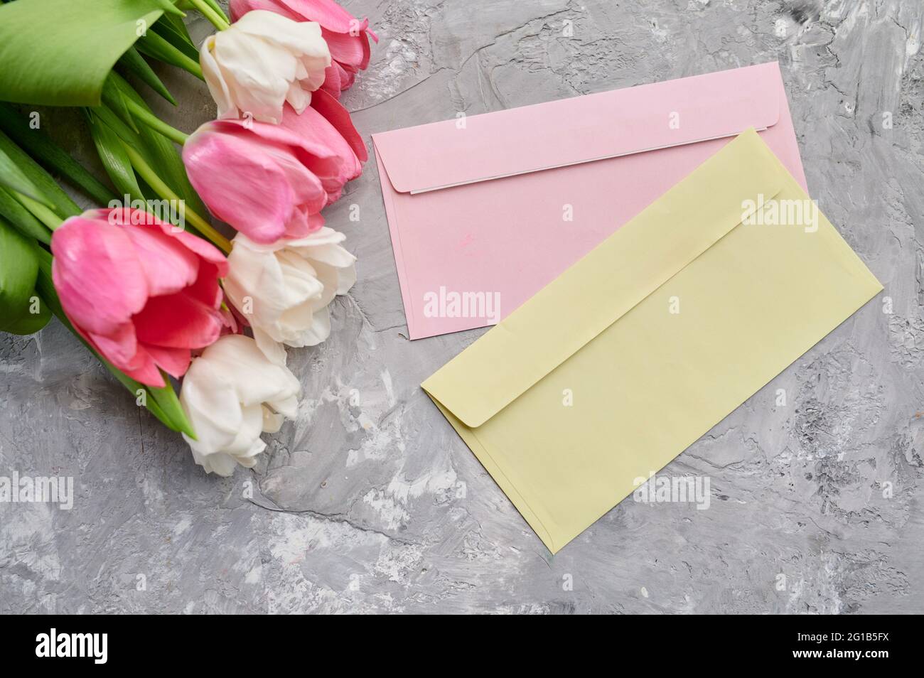 Tulips and envelopes on grunge grey background Stock Photo
