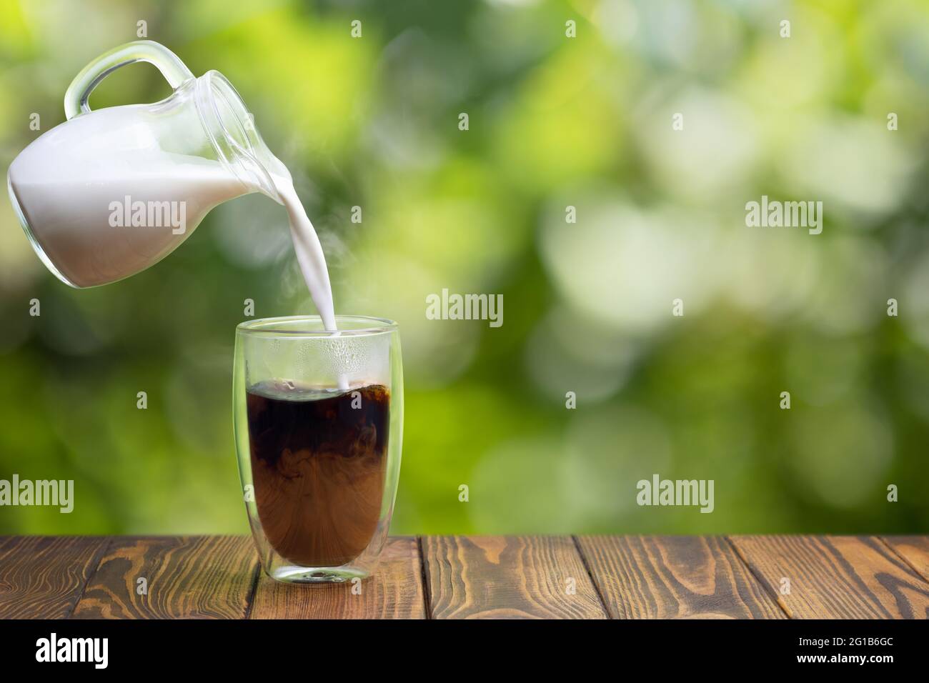 cream pouring from flying jug into glass of coffee Stock Photo