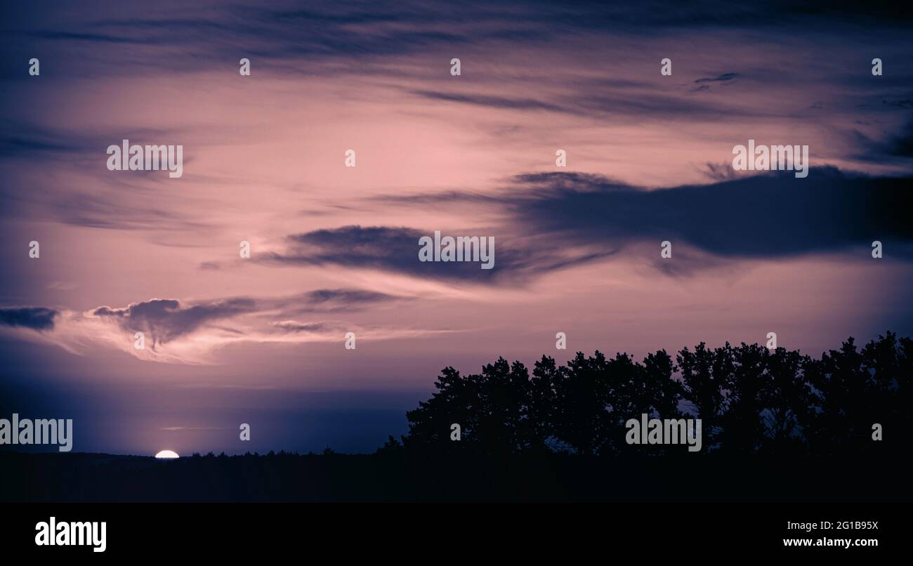 Eindrucksvoller Sonnenuntergang in stimmungsvoller Dark Melody Mood Melancholie - Farbenfroher Wolkenhimmel in Silhouette Stock Photo