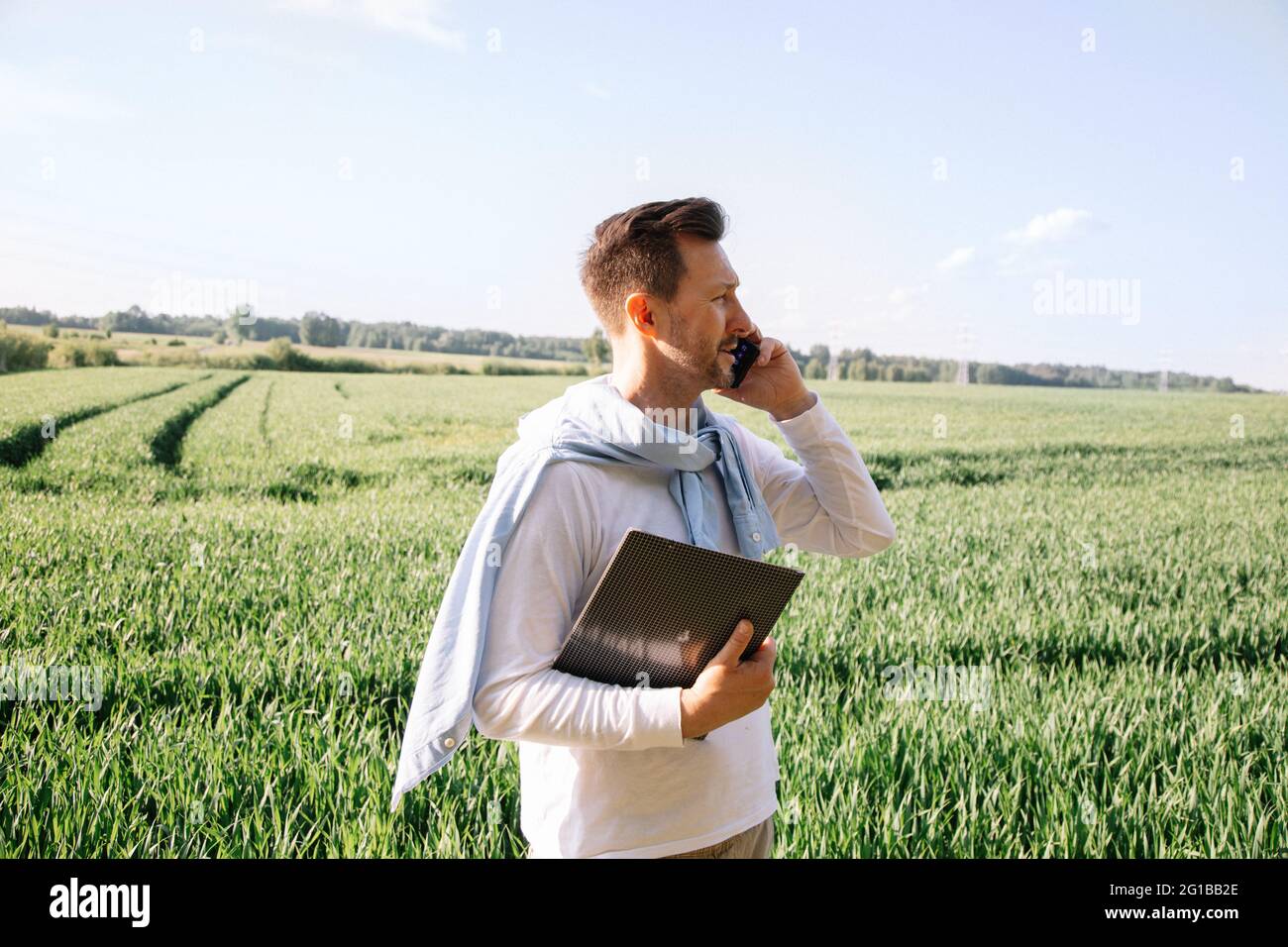 40-year-old young farmer checks his crop and negotiates deal on smart phone Stock Photo