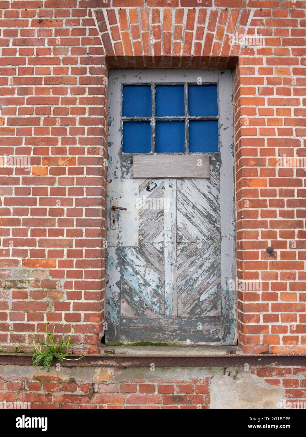 Old weathered wooden door with window in brick wall Stock Photo