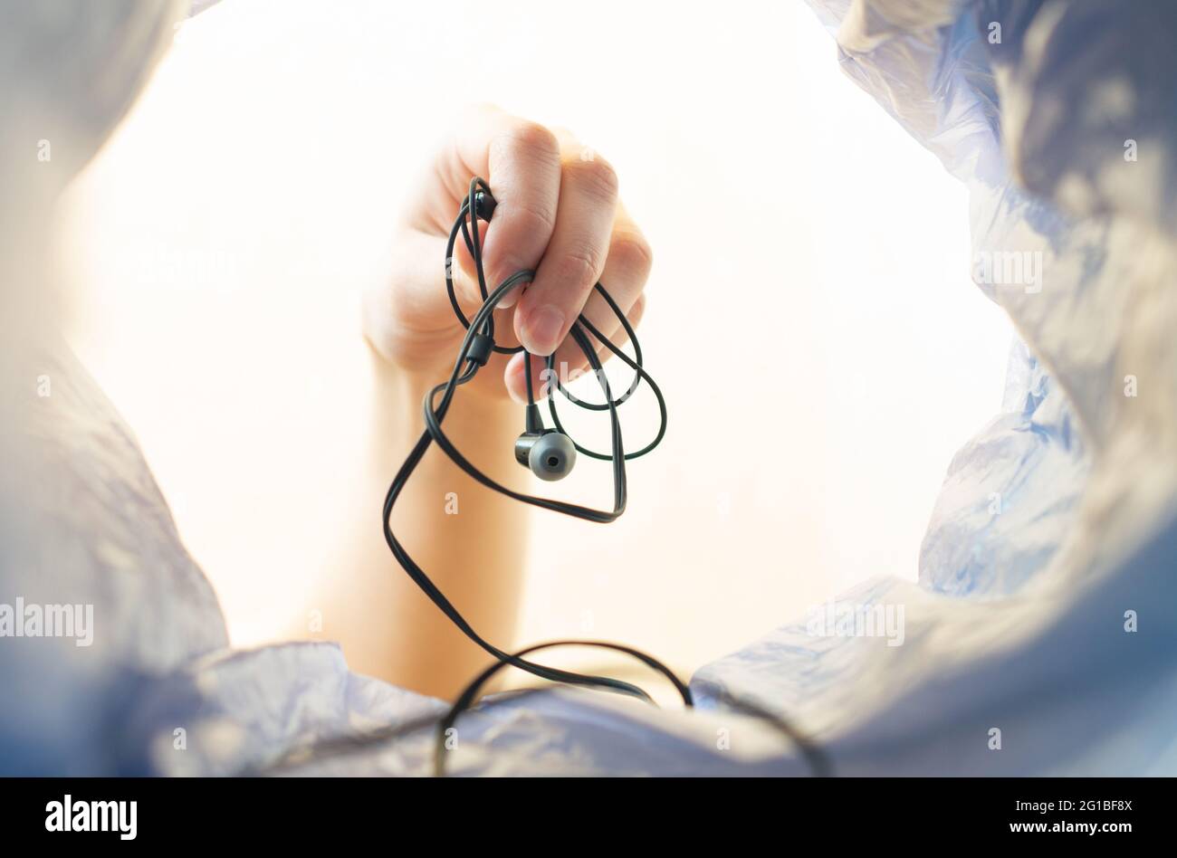 A woman's hand Throws the tangled headphones into the trash can. Stock Photo
