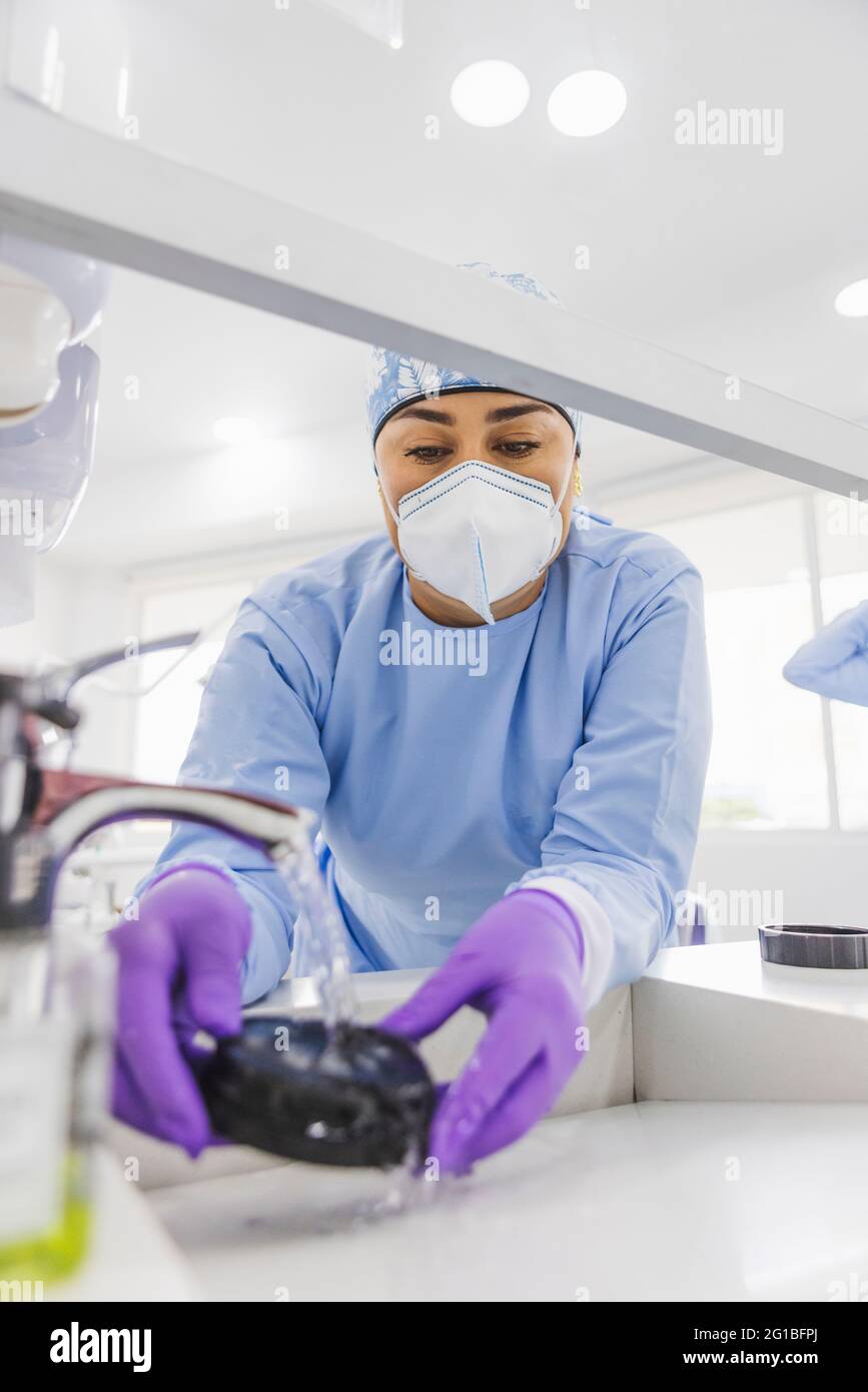From below crop dentist washing veneers with clean water in sink in