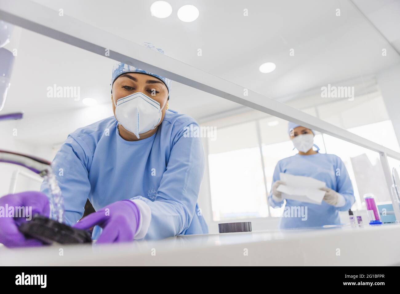 From below crop dentist washing veneers with clean water in sink in