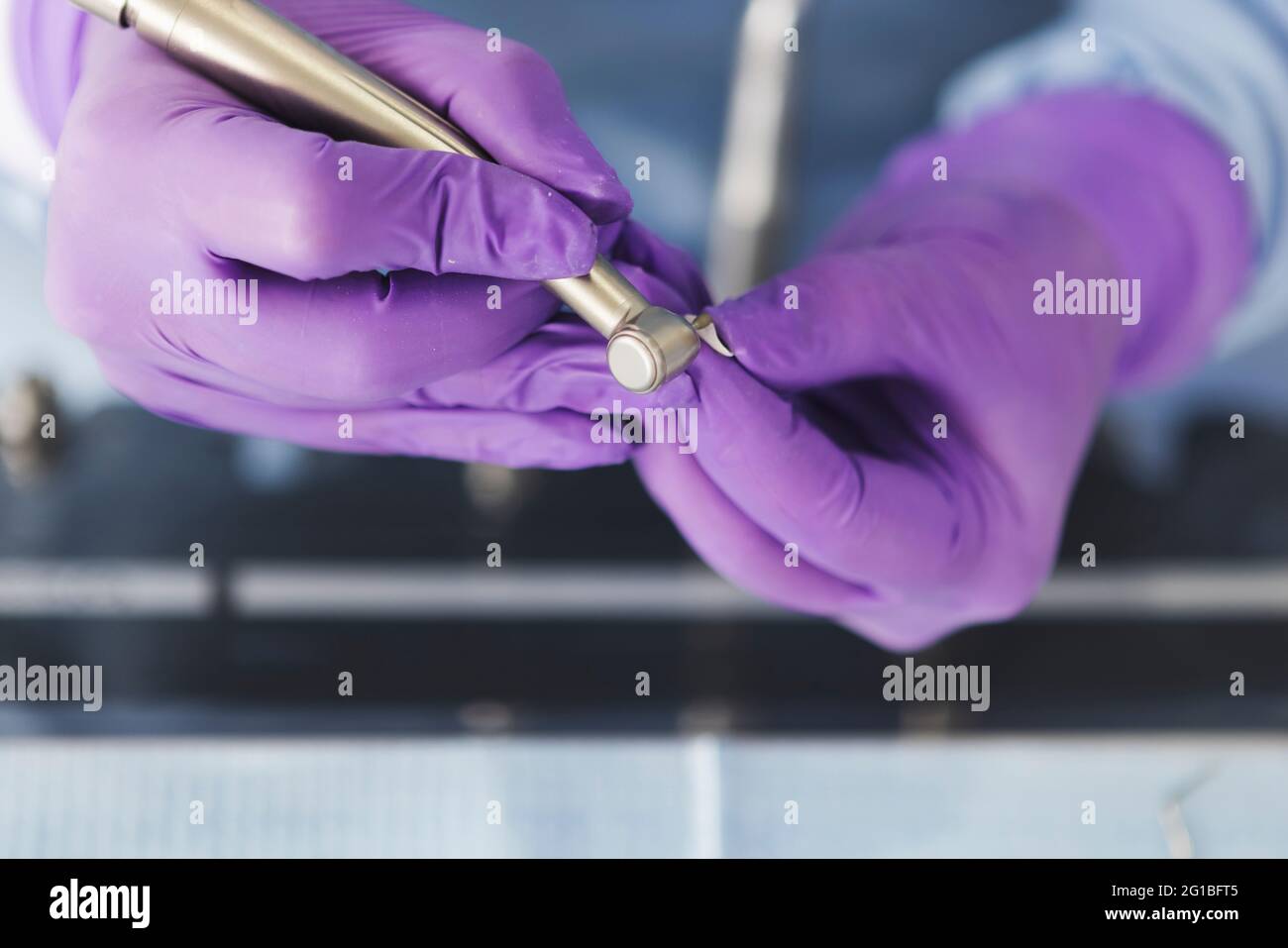 Crop dentist in gloves working with drilling machine in dental clinic Stock Photo