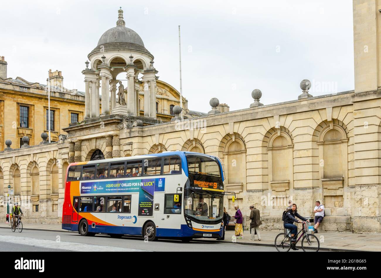 A bus stops outside University of Oxford, Queen's College on the High Street in Oxford, UK. Stock Photo
