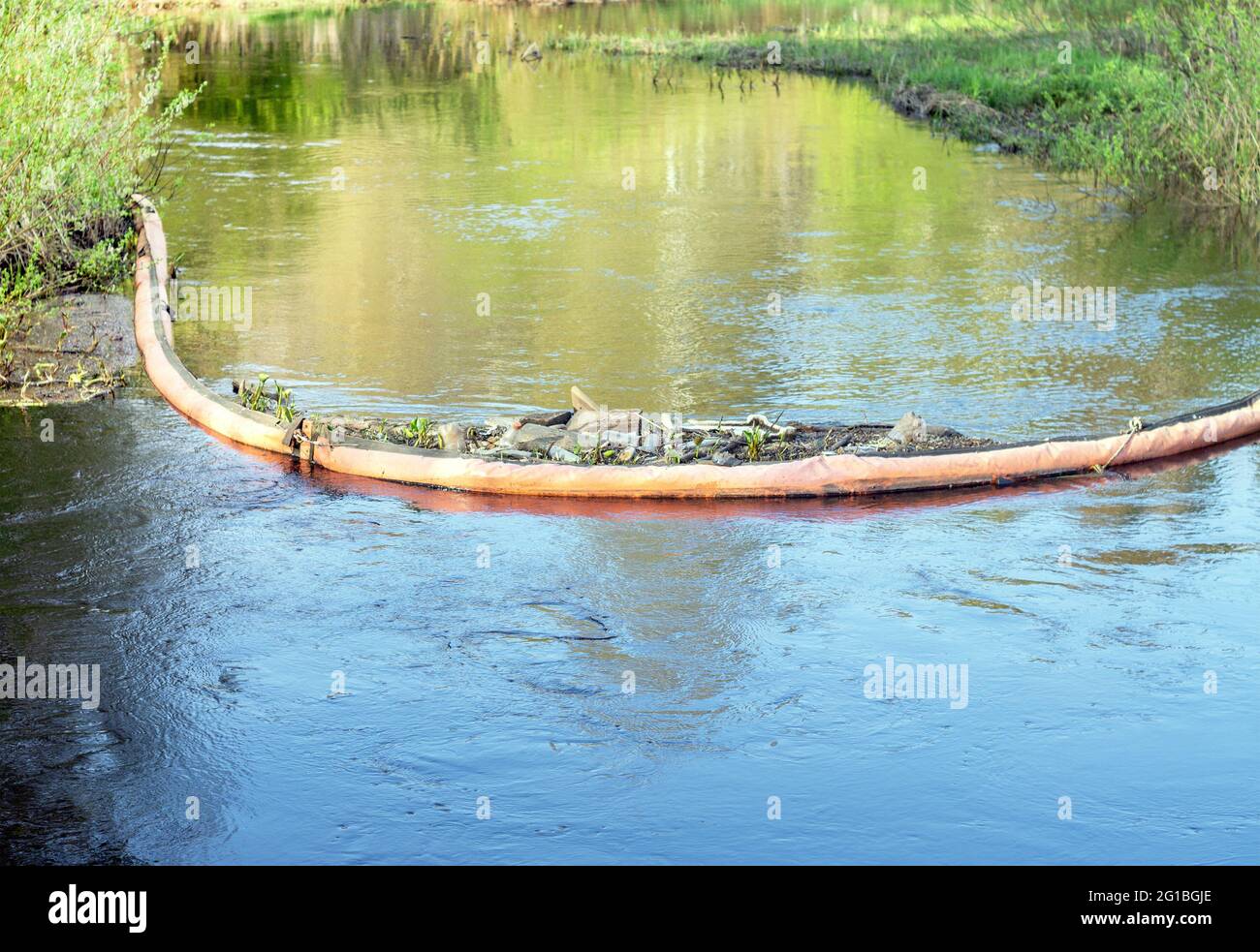 The floating barrier collects river waste to trap plastic bags, bottles, and other waste.Protection of rivers from garbage. Stock Photo