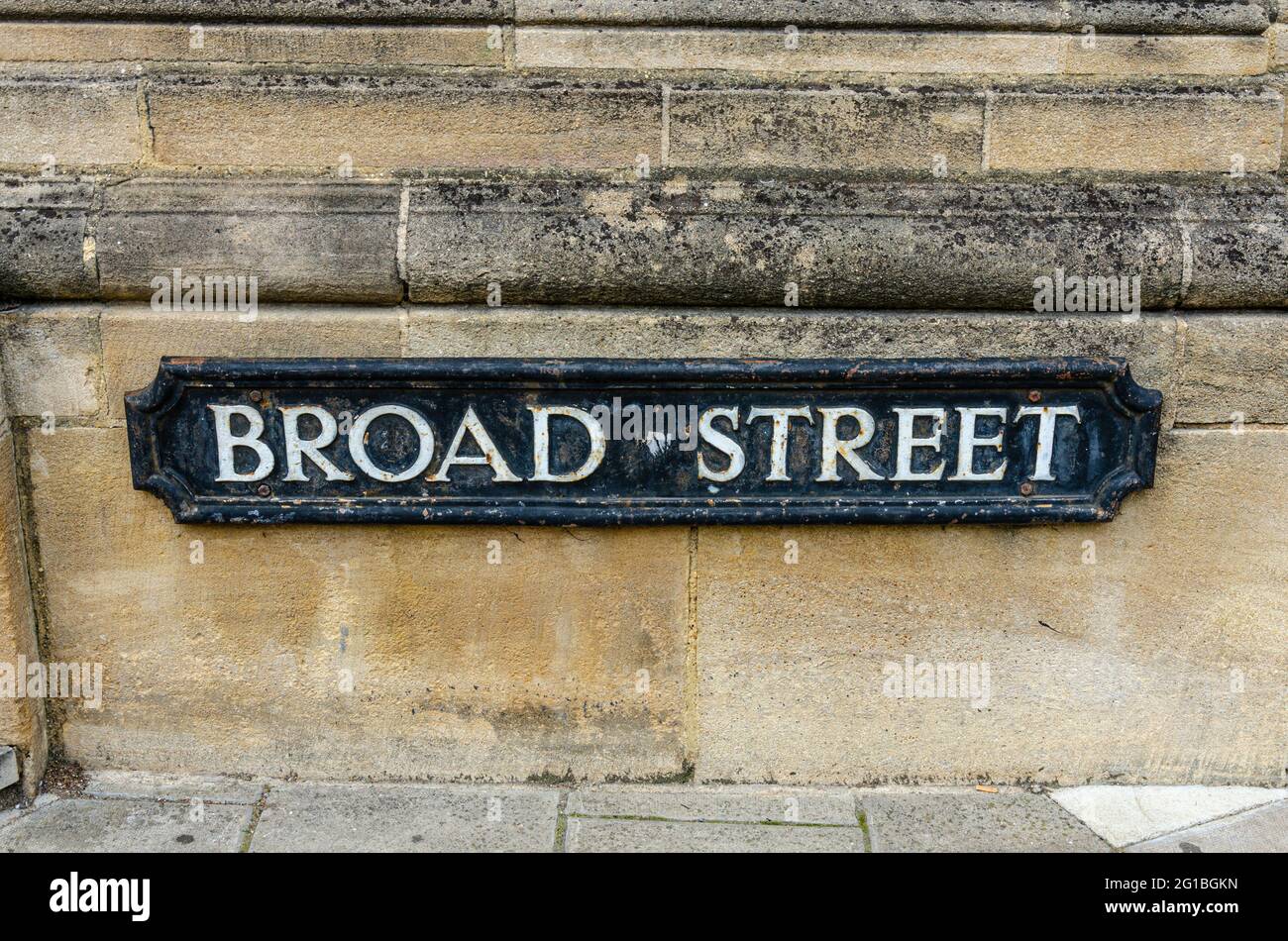 A street name sign on a yellow sandstone built wall for Broad Street in Oxford, UK Stock Photo
