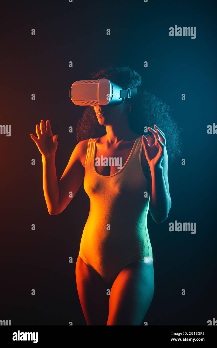 Anonymous ethnic female exploring virtual reality in headset on black background Stock Photo