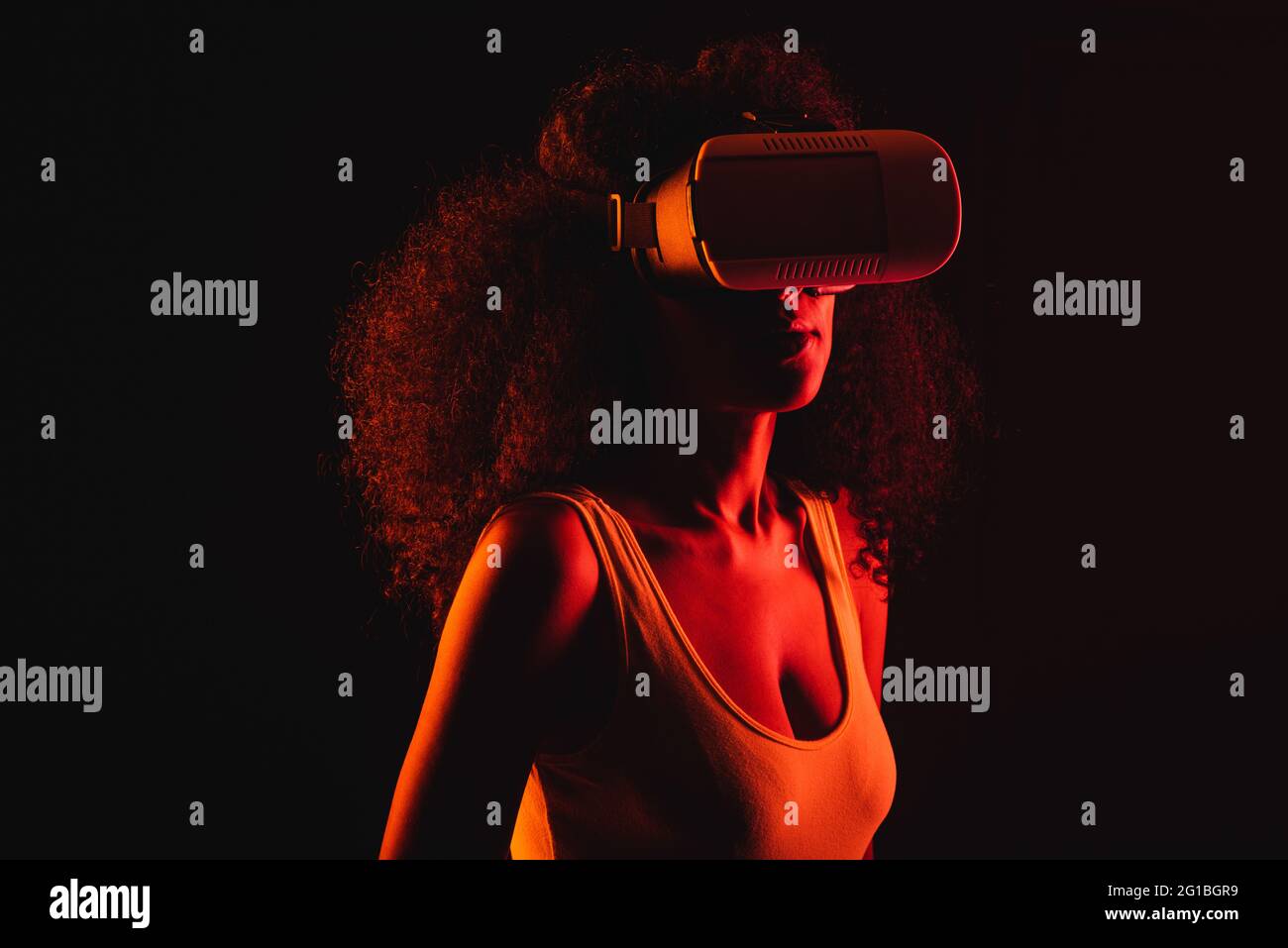 Anonymous ethnic female exploring virtual reality in headset on black background Stock Photo