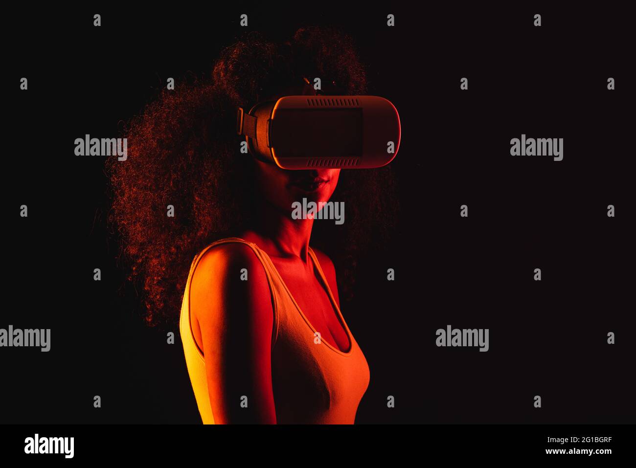 Anonymous ethnic female exploring virtual reality in headset on black background Stock Photo