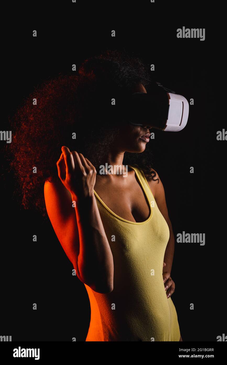 Anonymous ethnic female exploring virtual reality in headset on black background Stock Photo