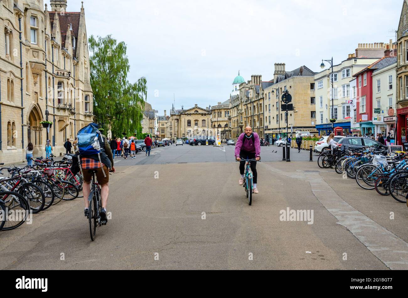 A view along Broad Street in Oxford, UK with a couple of cyclists passing each other. Stock Photo