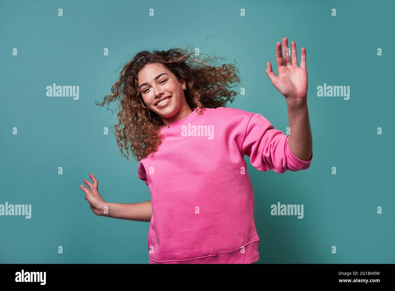 Positive young female jumping smiling looking at camera against blue background Stock Photo