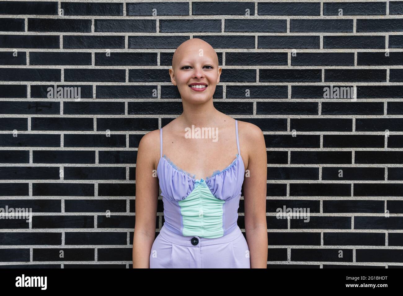 Confident young bald lady in colorful shirt and makeup standing near ...
