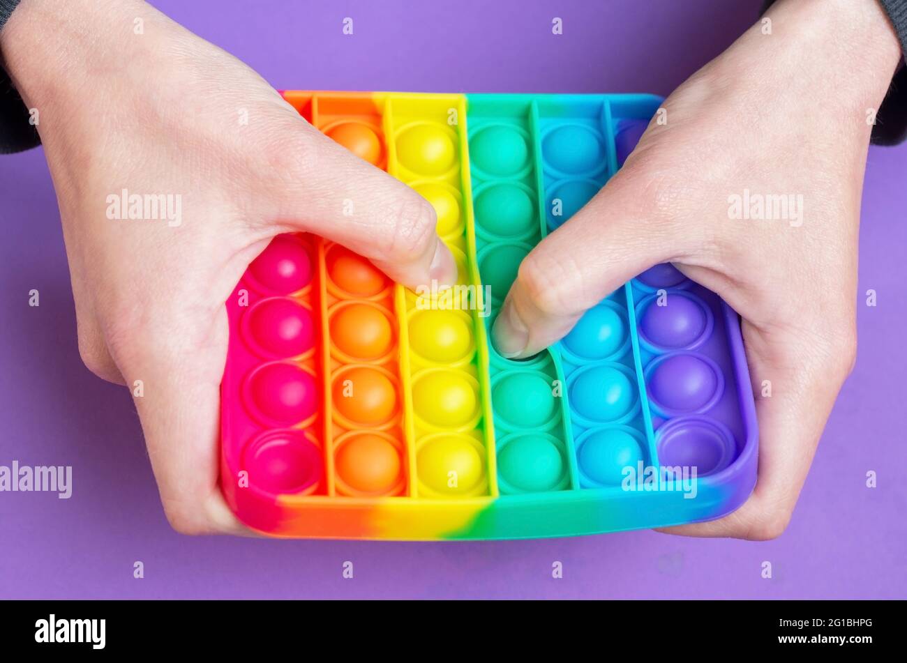 Woman play in sensory anti stress Pop It simple dimple in square shape toy. Push pop bubble flexible fidget sensory toy provide discharge. Stock Photo