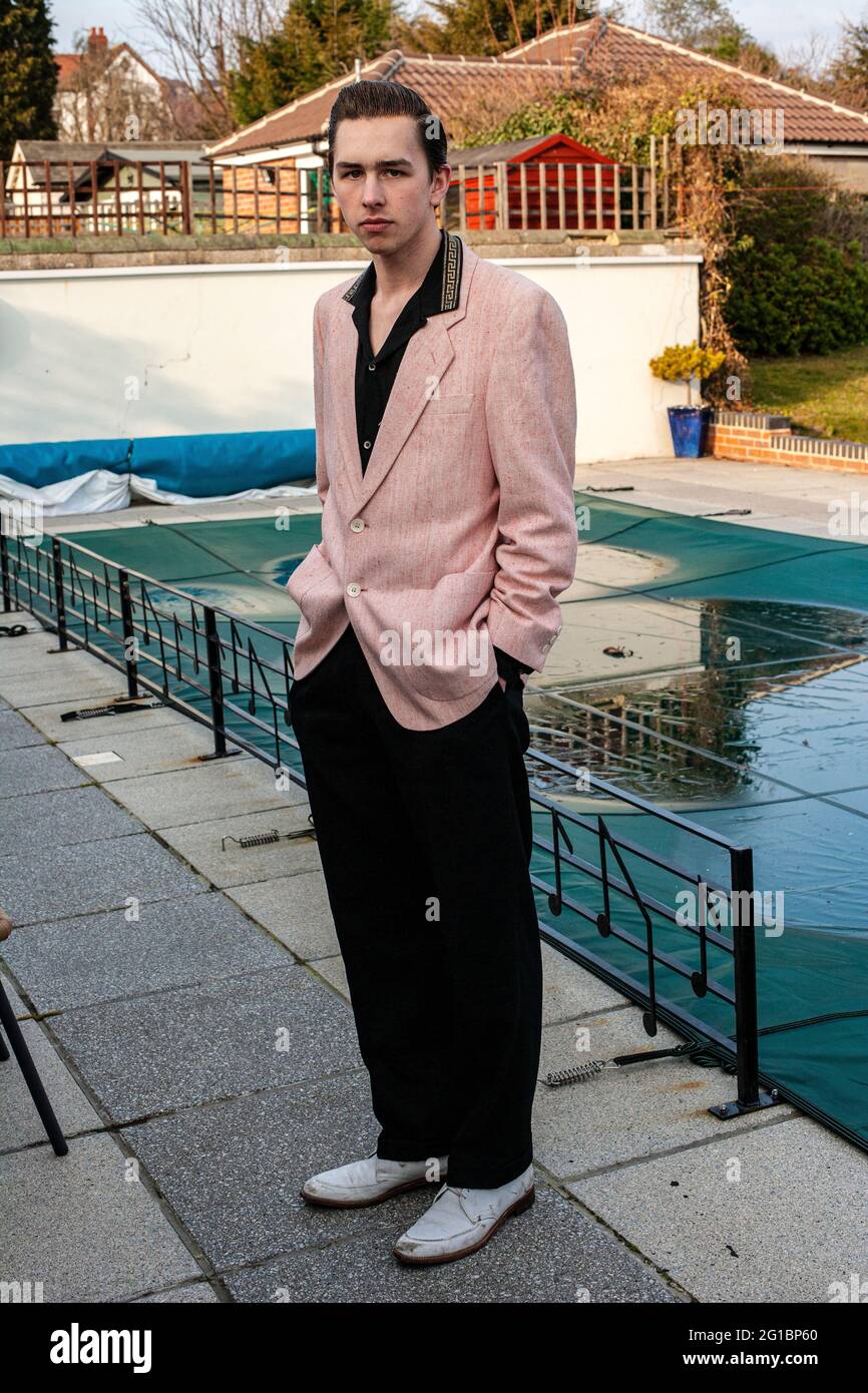 Young man wearing a pink suit jacket  standing next to the covered swimming pool Stock Photo