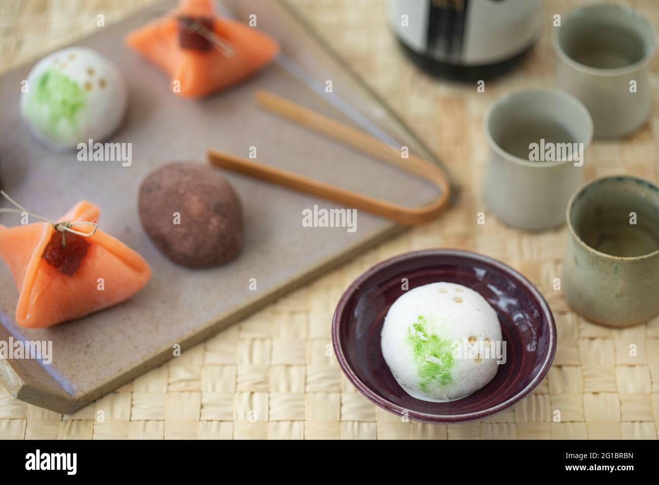 Ceramic tray with small Japanese sweets wagashi, and sake ceramic small cups. Stock Photo