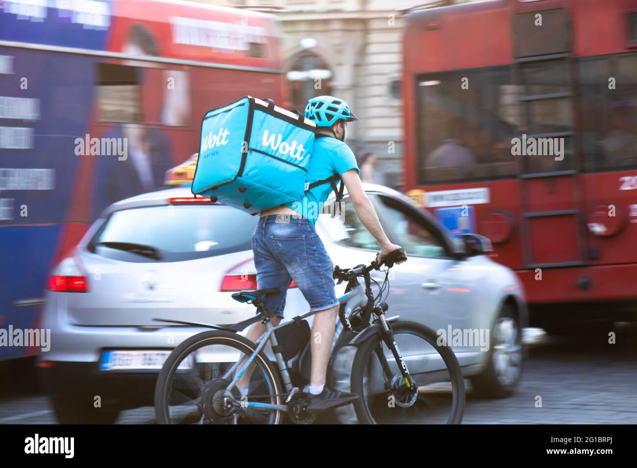 Belgrade, Serbia - June 5, 2021: Wolt food delivery service courier riding a bike in busy city street traffic Stock Photo
