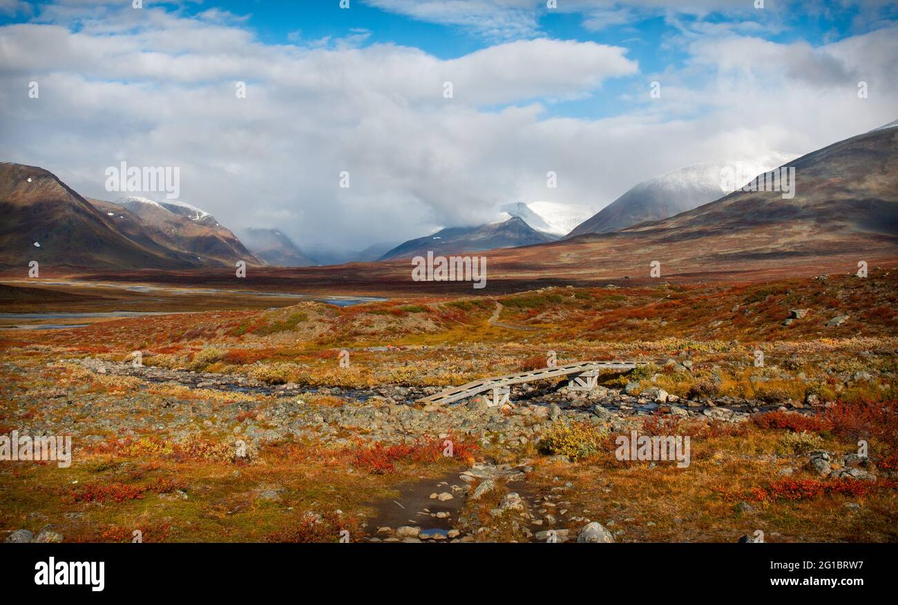 Amazing valley on the way of Kungsleden trail between Salka and Singi with a small bridge crossing a stream, Swedish Lapland, mid-September Stock Photo