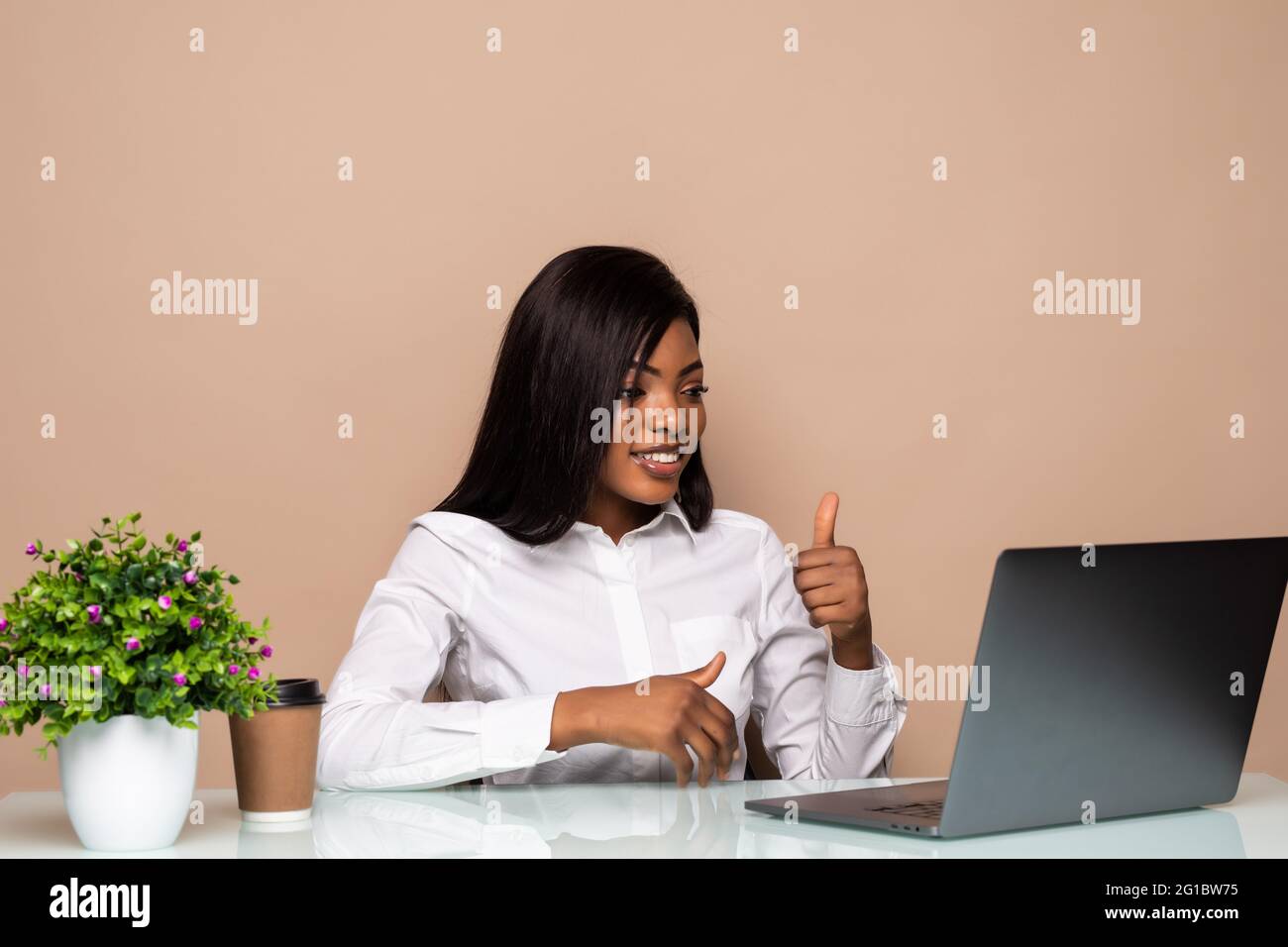 Young African businesswoman sitting at the desk in the office and video ...