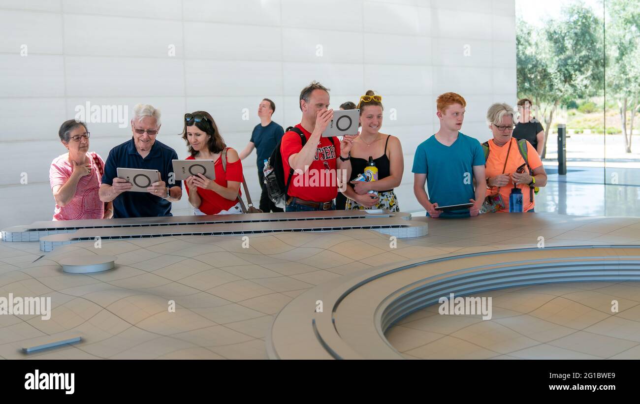 Cupertino, CA, USA - August 2019: Apple Store Cupertino with people looking at Infinite Loop Apple Headquarters through virtual reality using iPad tab Stock Photo