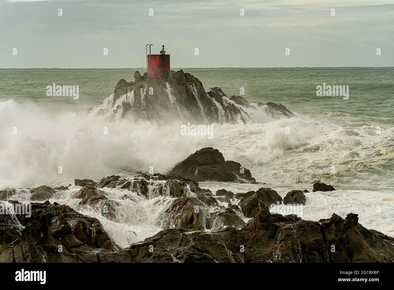 Dramatic storm waves smashing and splashing around North Rock and it's red beacon at Mount Maunganui, New Zealand. Stock Photo