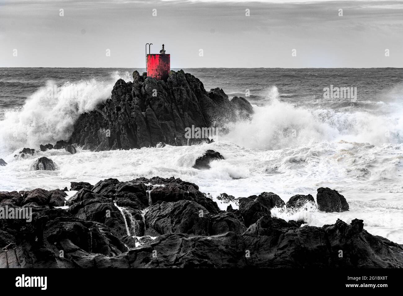 Dramatic storm waves smashing and splashing around North Rock and it's red beacon at Mount Maunganui, New Zealand. Stock Photo