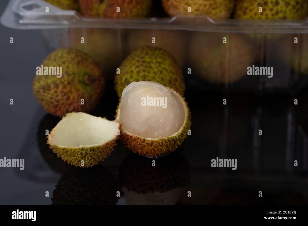 A close-up of a peeled green lychees with blurred whole fruit in the background. Selective focus points. Stock Photo