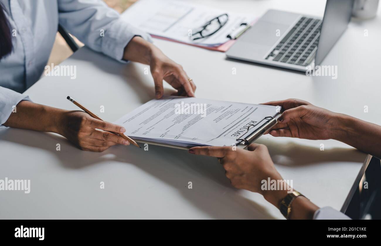 Businesswoman holding resume and talking to female candidate, during corporate meeting or job interview - business, career and placement concept. Stock Photo