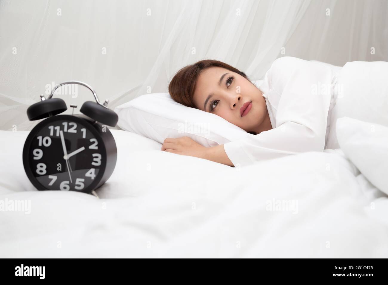 Asian women with feelings of helplessness and hopelessness on white bed in bedroom, Either insomnia, Depression symptoms and warning signs concept Stock Photo
