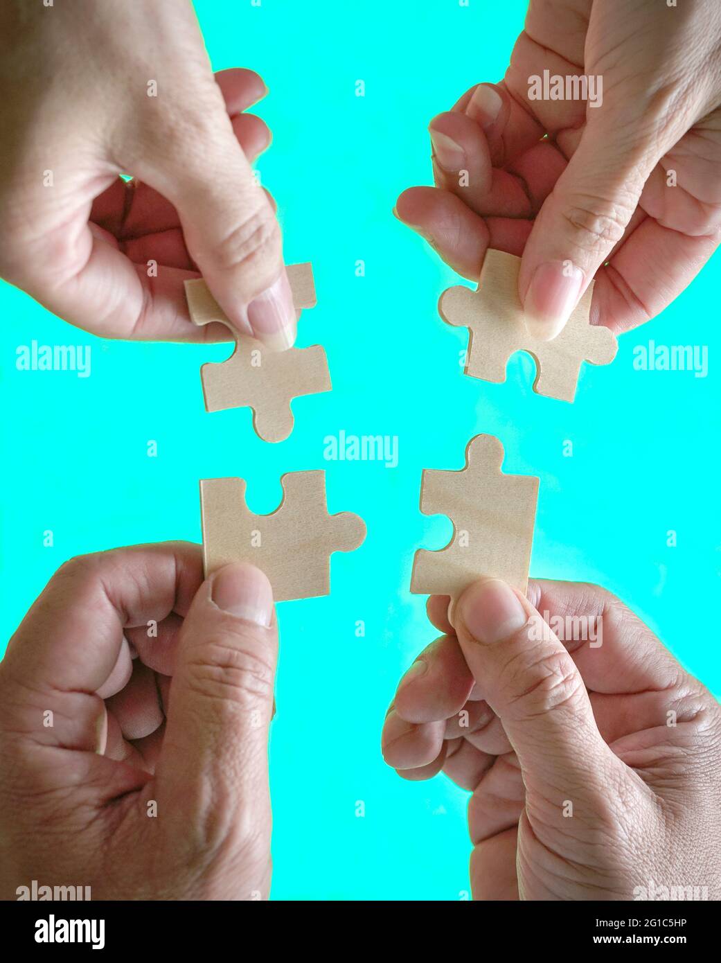 Business people assembling jigzaw puzzle. Close up shot. Concept of cooperation, teamwork and support. Top view. Stock Photo