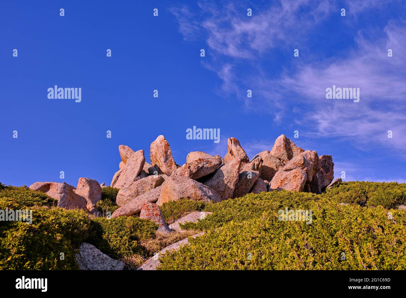 Exquisite rock formations among the juniper bushes on a background of blue sky with clouds Stock Photo