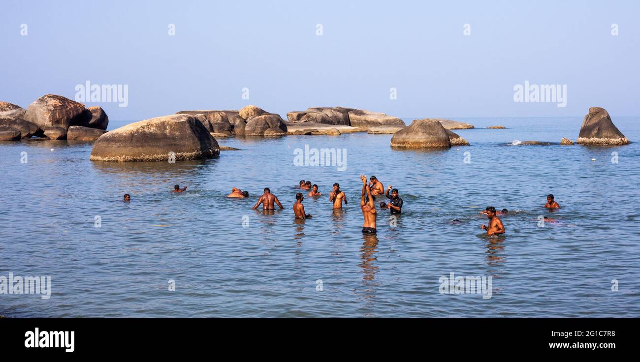 Group of Indian men bathing near beautiful rock formation,Agonda Beach