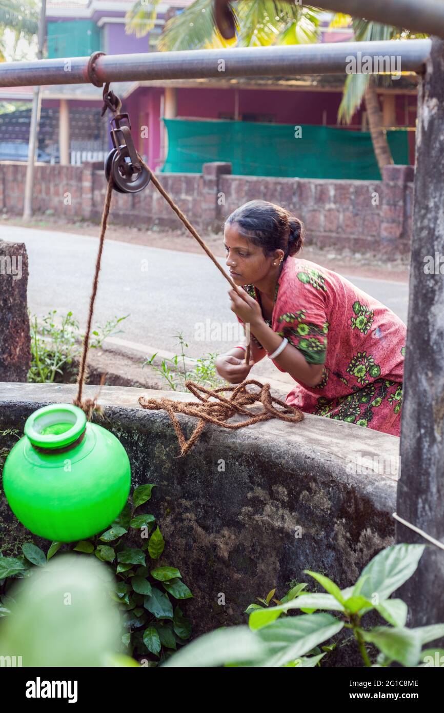 Indian female draws water from well using traditional rope and pulley system, Agonda, Goa, India Stock Photo