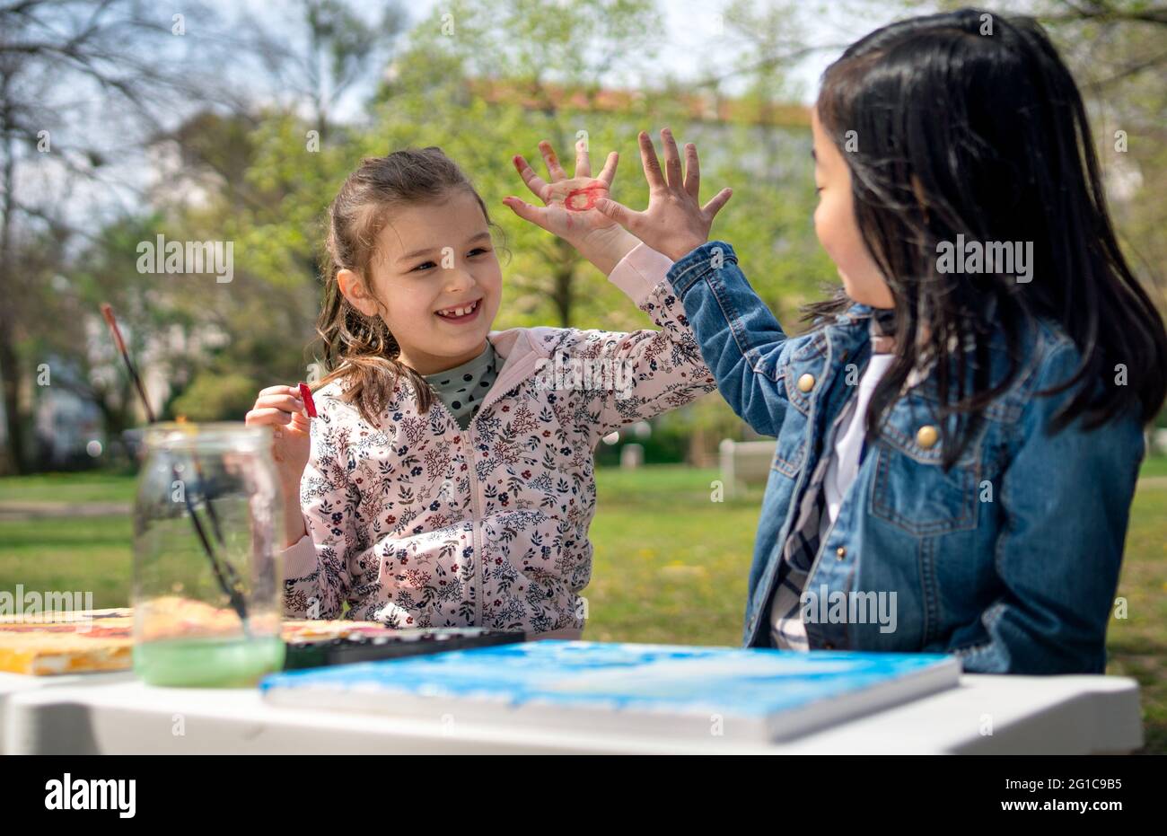 Small children painting pictures outdoors in city park, learning group education concept. Stock Photo