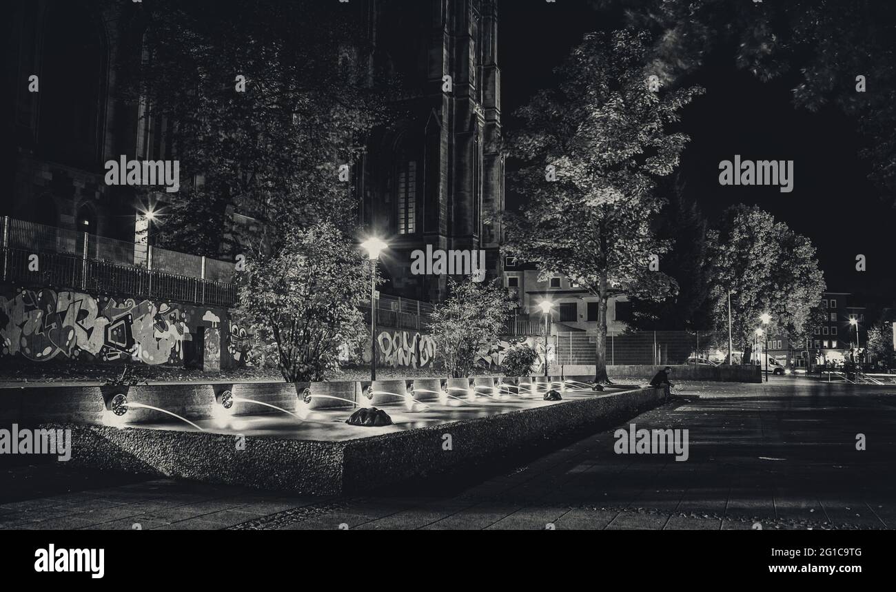 Im Herzen des Ruhrgebiets in der Essener Innenstadt bei Nacht an einem warmen Spätsommerabend. Cafe Nord bei der St. Gertrud Kirche am Brunnen Stock Photo