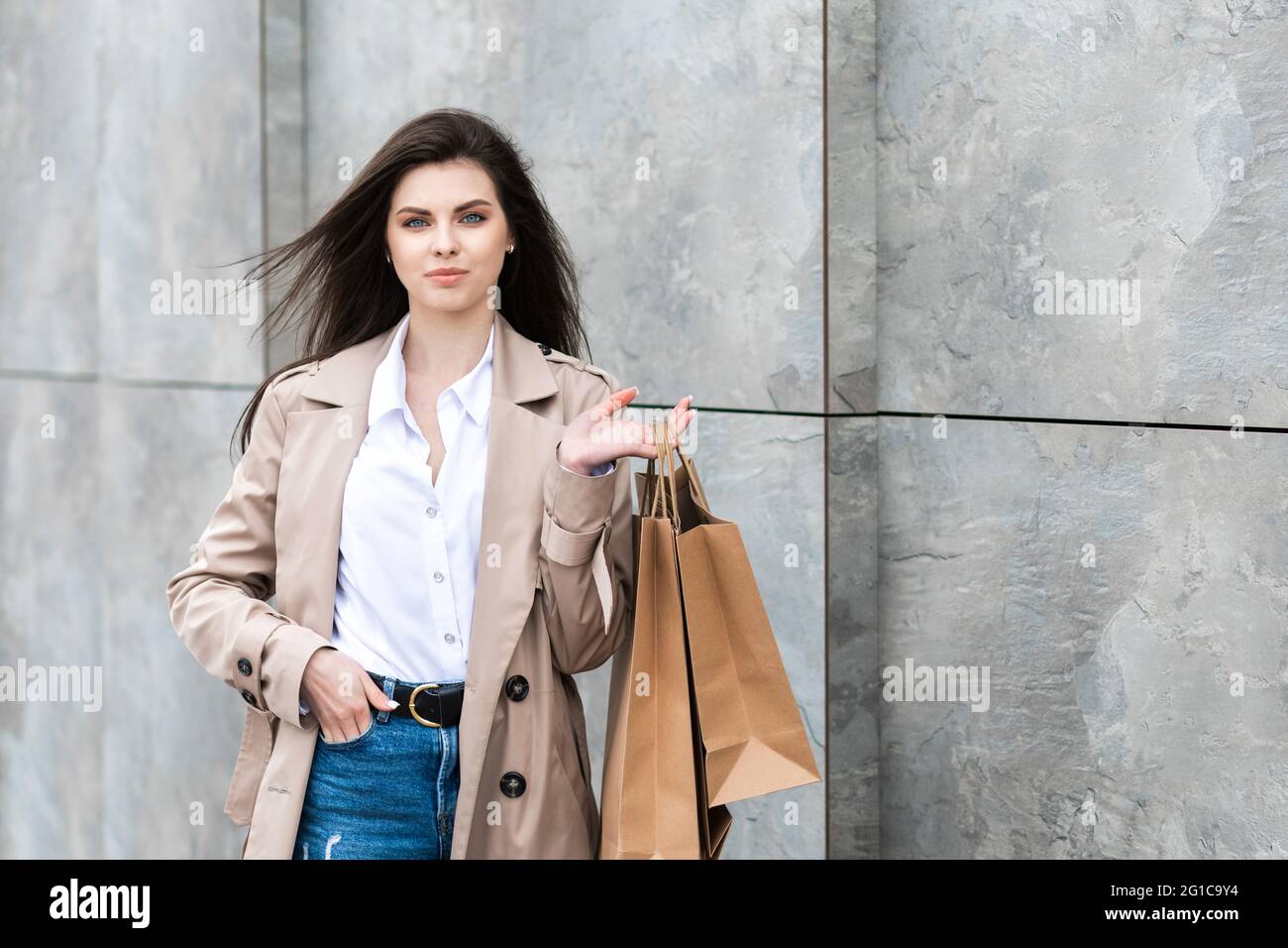 A girl in a casual clothes with shopping bags and lots of purchases near  the shopping center smiling hands you her package, consumerism sale and  peopl Stock Photo - Alamy