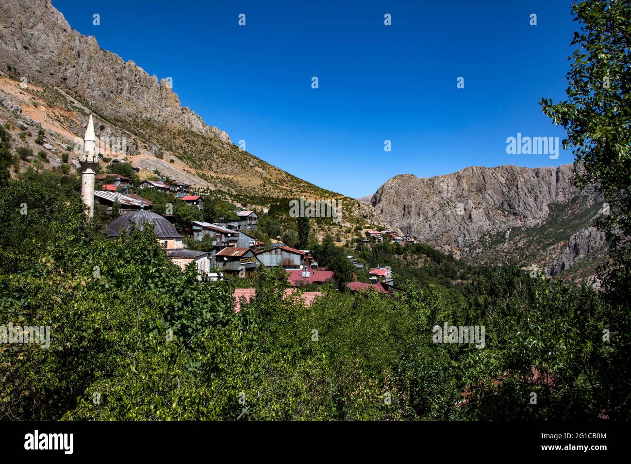 This scenery of Erzincan reflects the amazing natural elements of this place. Buildings and a mosque in the forest surrounded by mountains under the b Stock Photo