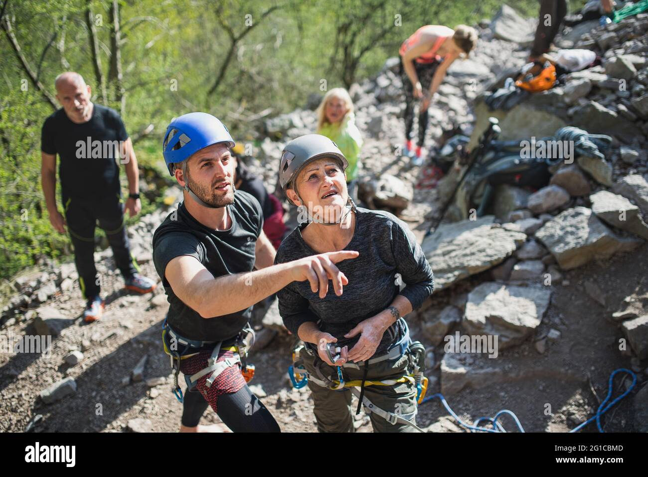 Group of seniors with instructor climbing rocks outdoors in nature ...